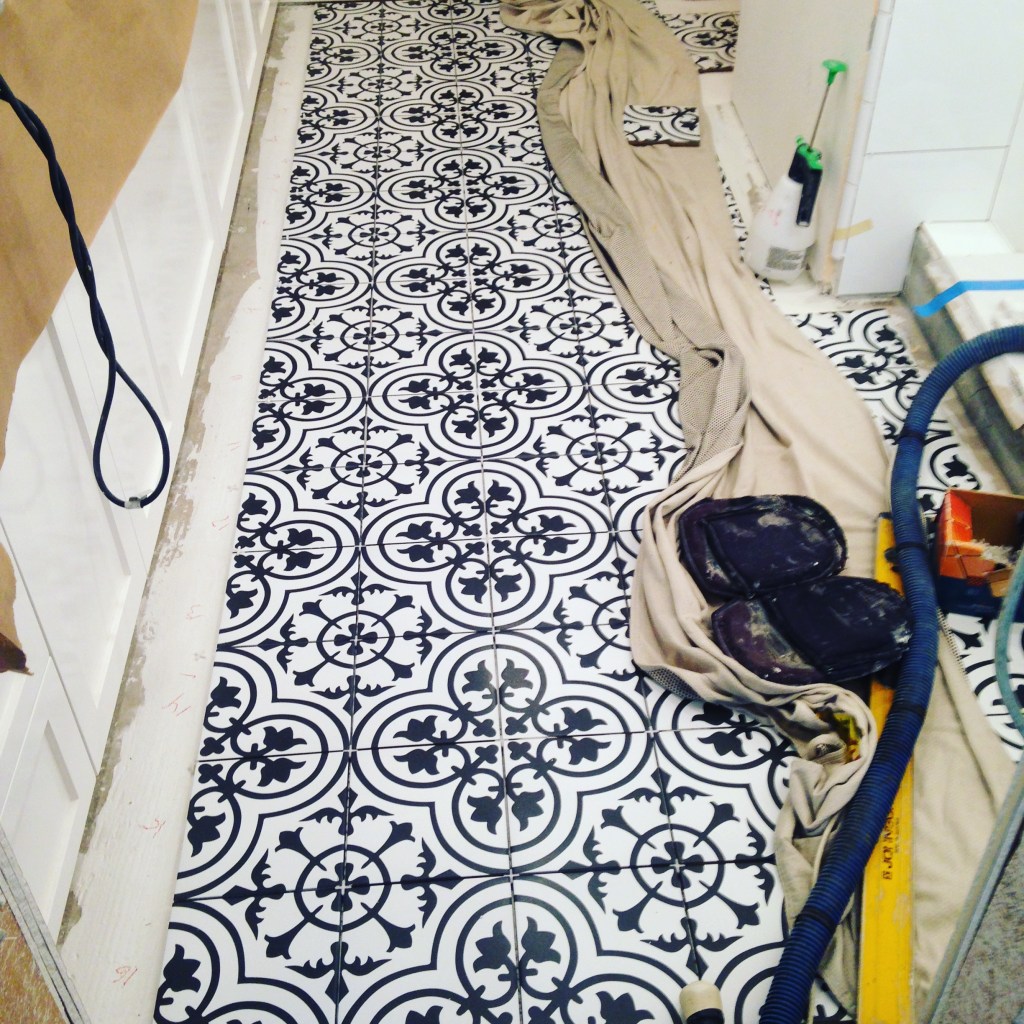 black and white moroccan floor tile pattern installed with equipment and materials laid out showing a bathroom remodel mid construction. 
