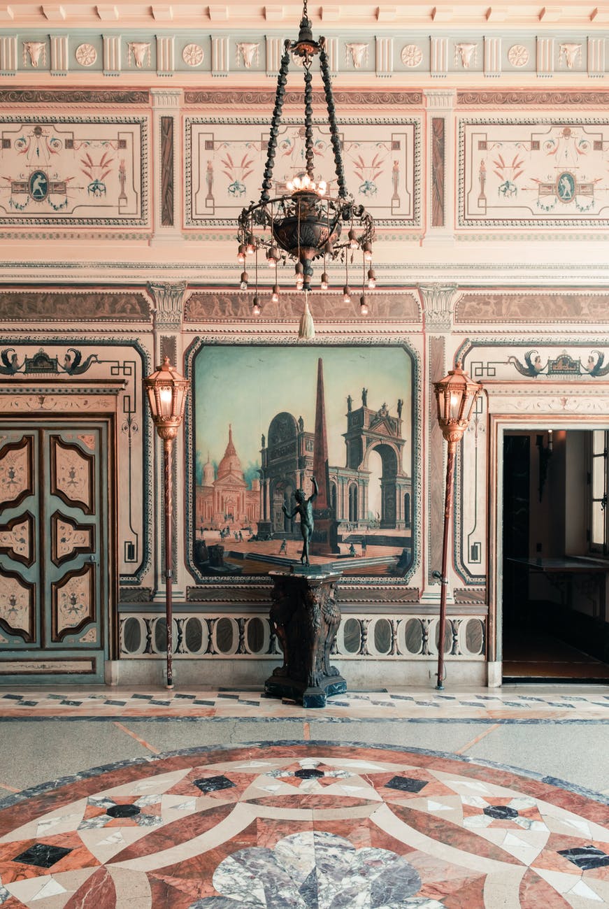 mansion castle hall with painted walls, chandelier and torches, pedestal with iron statue , and mosaic marble floor.how to home improvement advice.