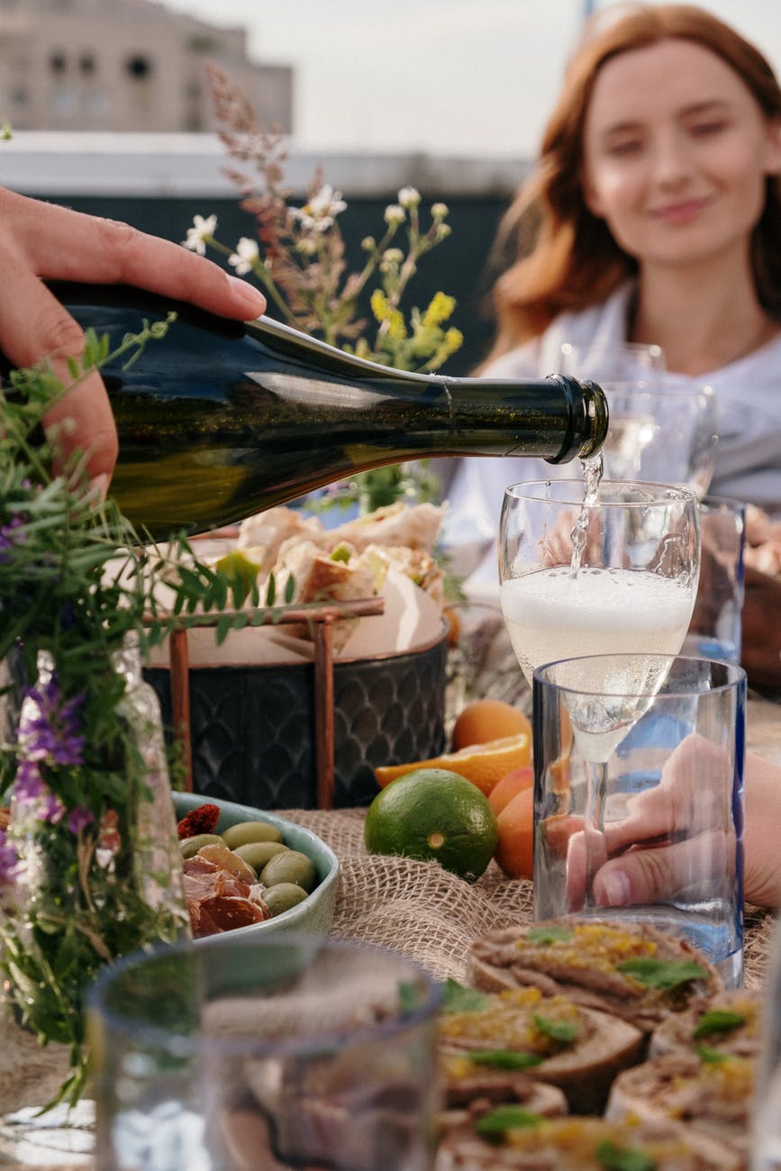 dining food with cheese board, limes, oranges, and champagne pouring into a glass.