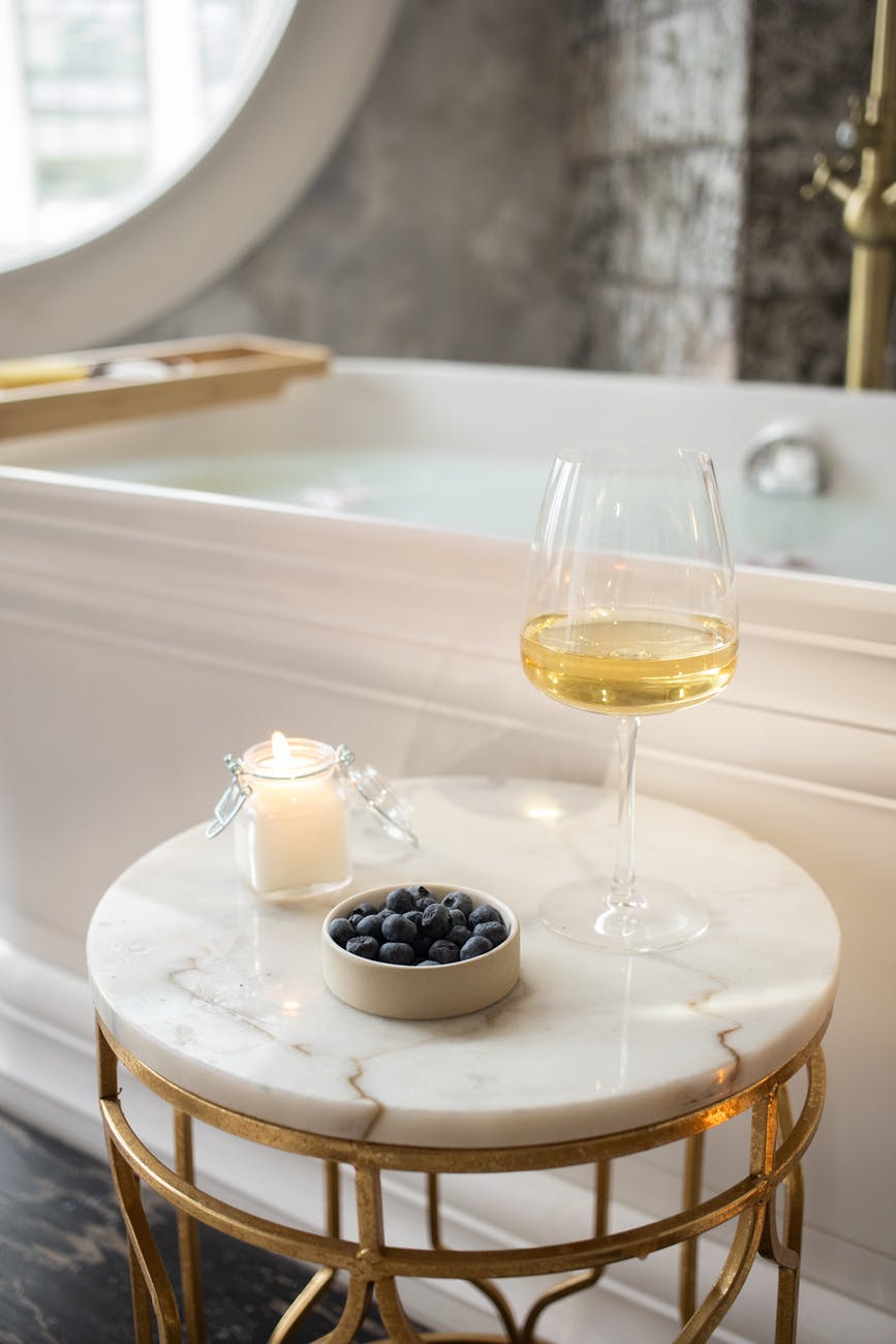 marble table with blueberries, wine, and candle next to a luxurious bath. how to home improvement advice.