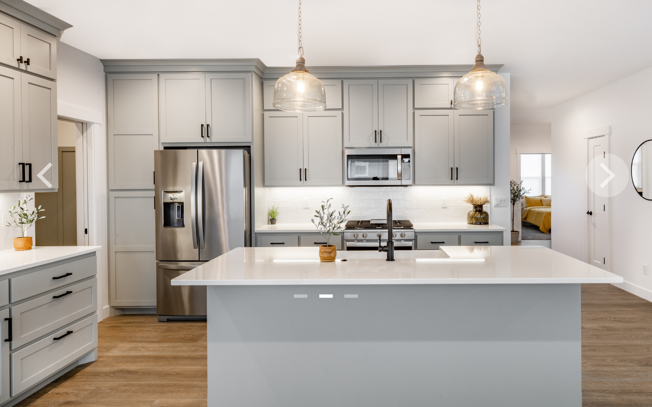 kitchen with light grey cabinets and white stone countertops and wood floors