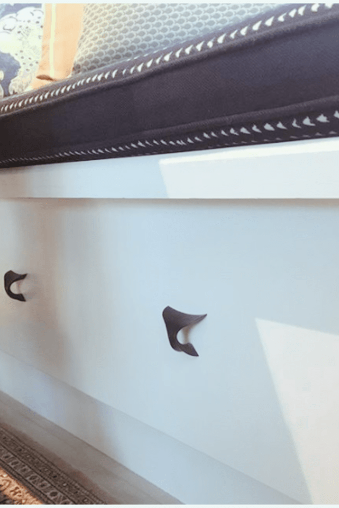 up close of banquette bench with black whale drawer pulls with indigo bench seat cushion, aqua fish pattern pillows