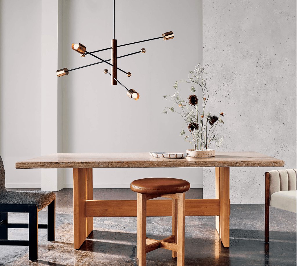 CB2 Norte WalnutWood and Brass Chandelier over a natural wood modern dining table and light grey walls in background