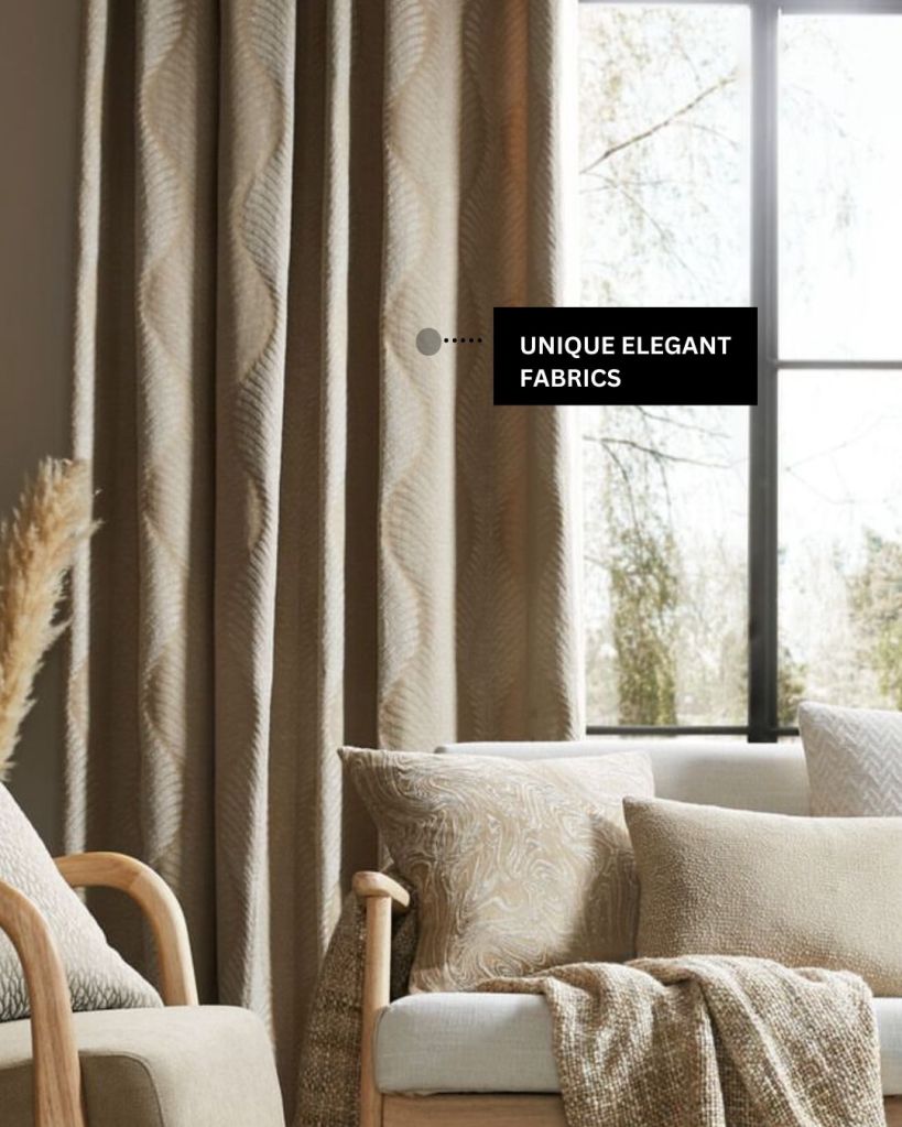 An image showcasing a cozy living room with drapery panels in neutral tones. Text on the image reads: "UNIQUE ELEGANT FABRICS."